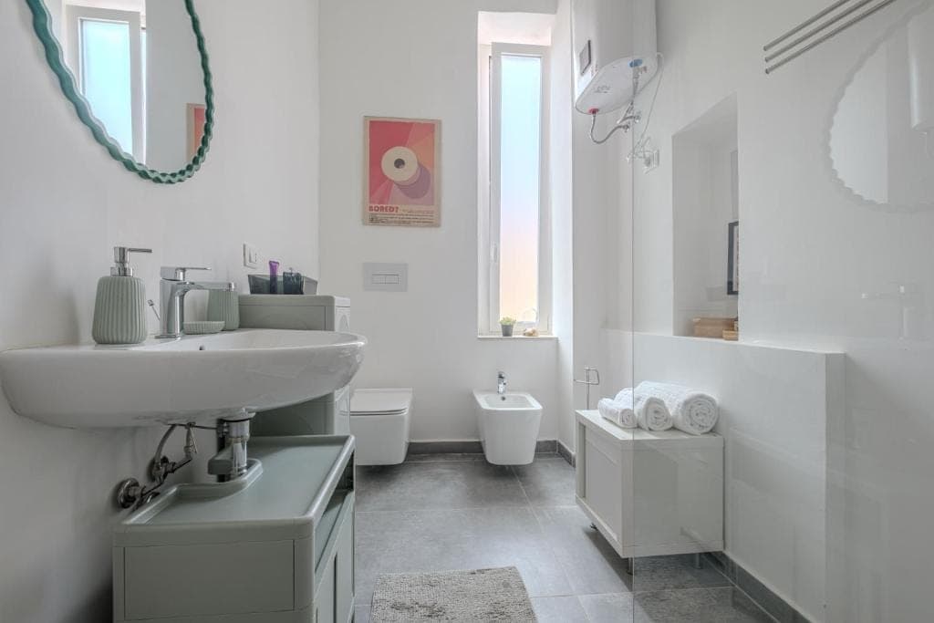 The bathroom with basin, bidet and the shower behind a low wall
