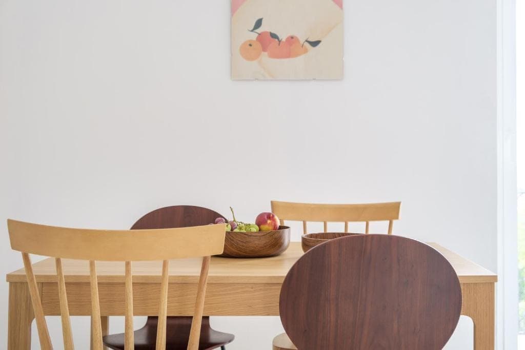 The wooden dining table with its chairs and a bowl of fruit, backlit
