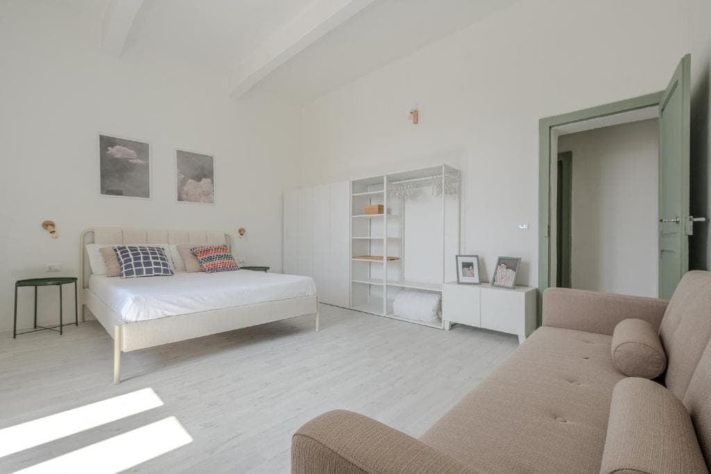 The double bedroom with the open wardrobe and a sofa at the foot of the bed