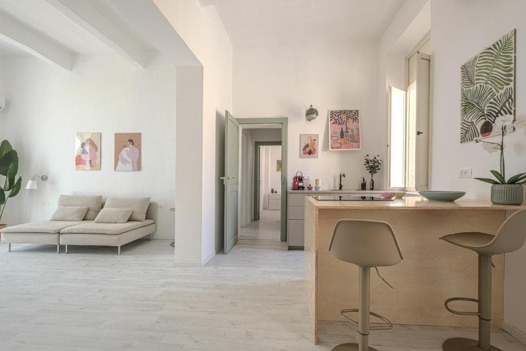 The living room opening onto the kitchen, with the hallway and sage-green doors