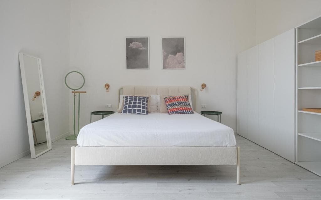 The double bedroom with a floor mirror and prints above the headboard
