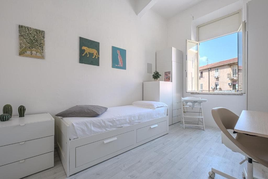 The small bedroom with a single bed, desk and a window onto the neighbourhood